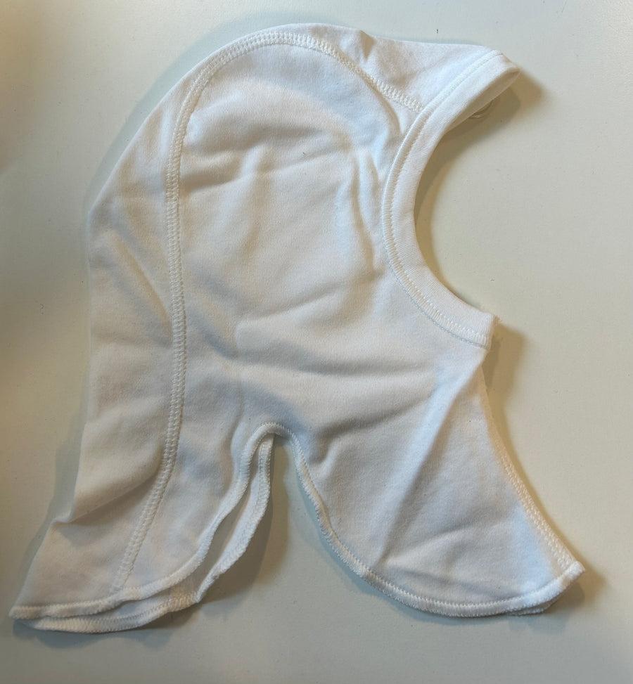 Hvid enkeltlags bomuldshue til baby lagt fladt ud med synlige overlock-sømme langs kanterne